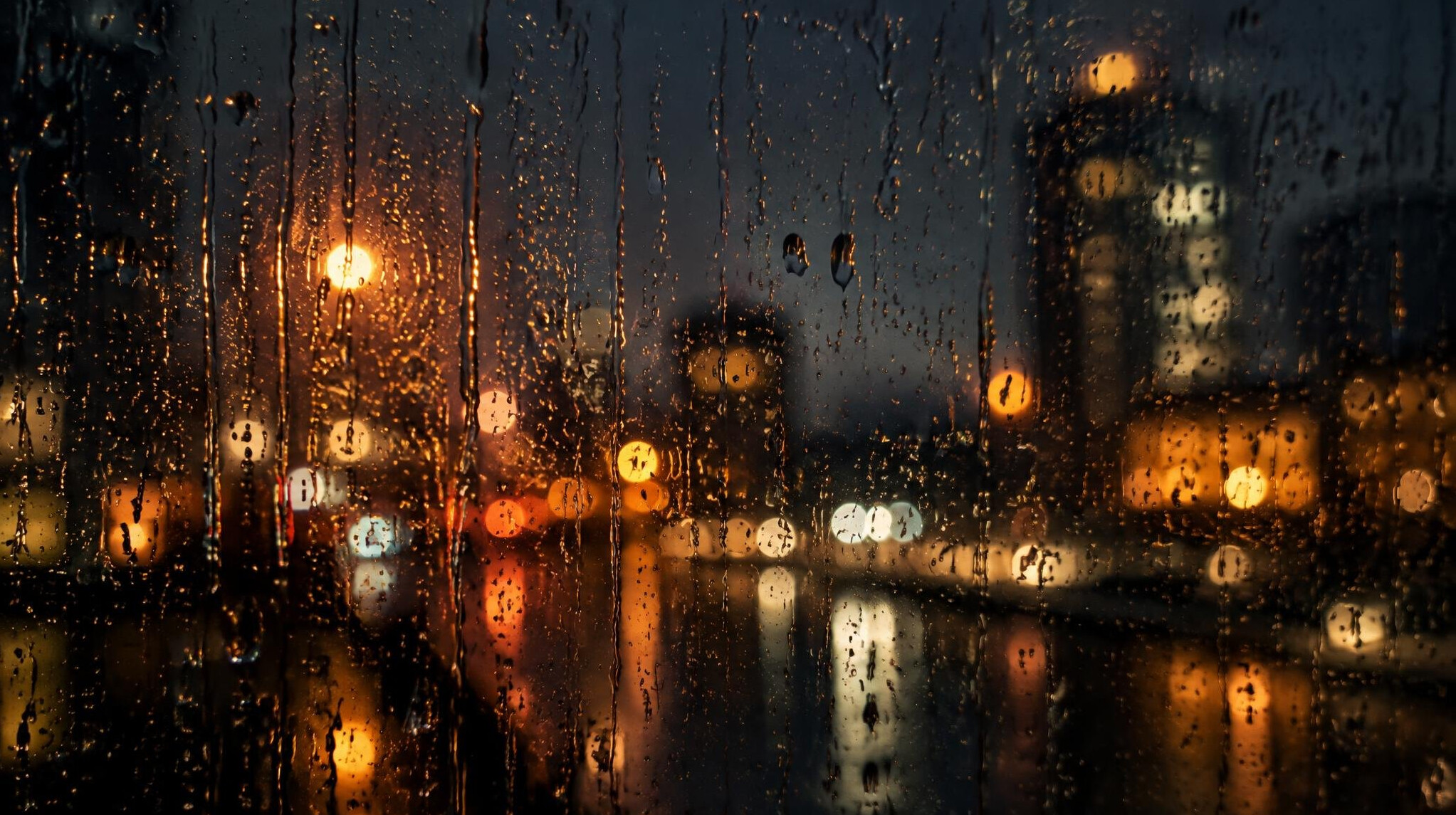 Raindrops on a window with blurred city lights at night